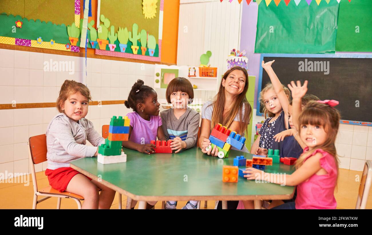 Glückliche Gruppe von Kindern im internationalen Kindergarten oder in der Nachschulpflege Zentrum zusammen mit einem Pädagogen Stockfoto