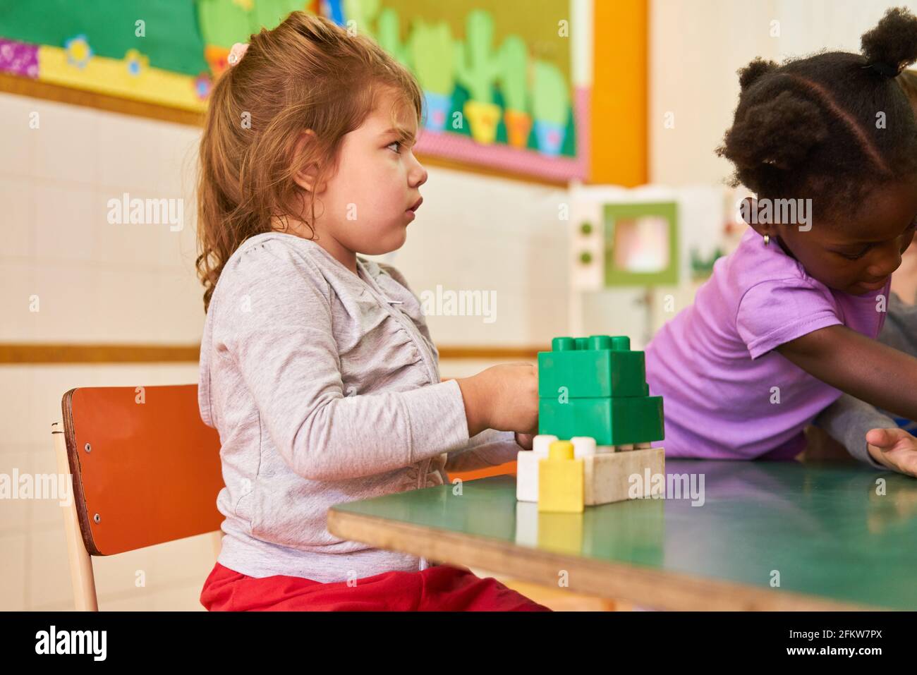 Mädchen im internationalen Kindergarten oder in der Vorschule spielen mit Bausteinen Am Tisch Stockfoto