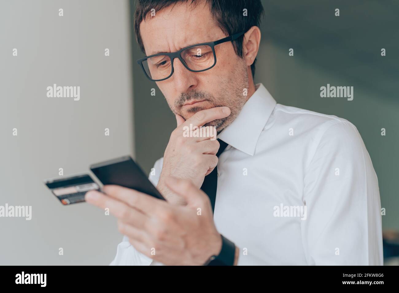 Mobile Banking im Geschäftsbüro, Geschäftsmann mit Smartphone und Kreditkarte, Nahaufnahme mit selektivem Fokus Stockfoto