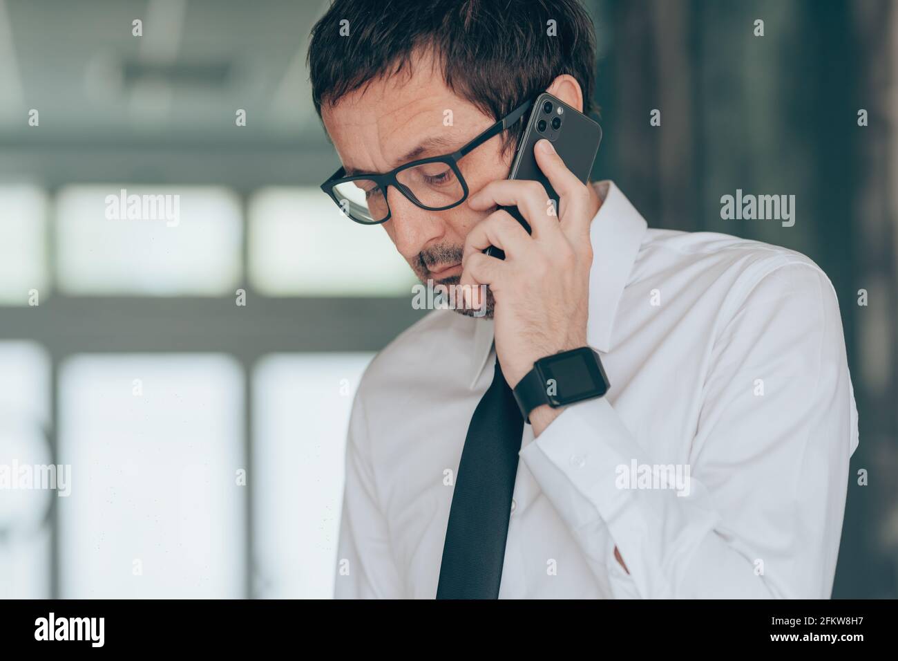 Seriöser Geschäftsmann, der im Büro auf dem Mobiltelefon spricht, selektives Porträt Stockfoto