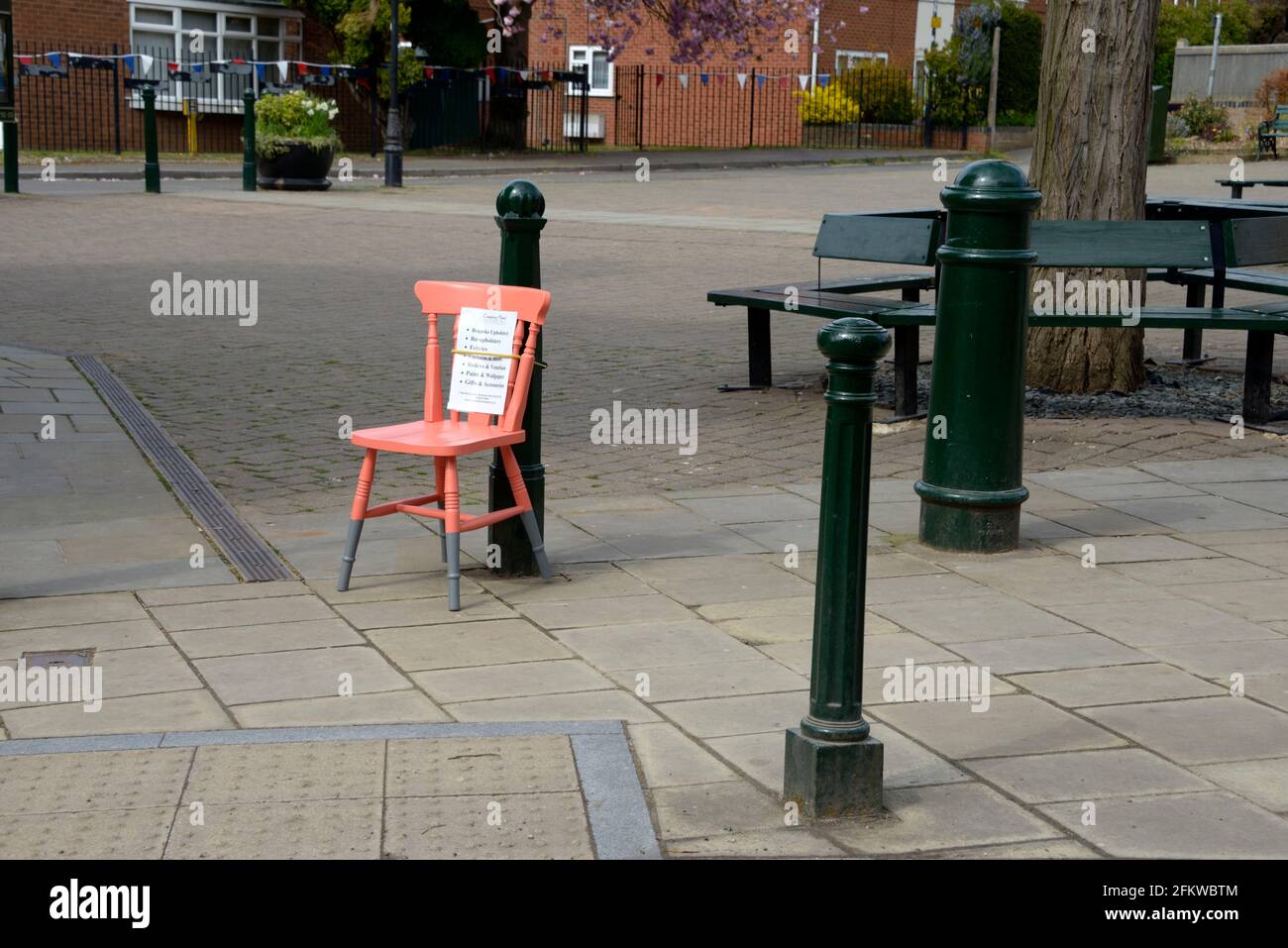 Orangefarbener Stuhl an einen Pfosten gebunden, mit einer Nachricht. Stockfoto