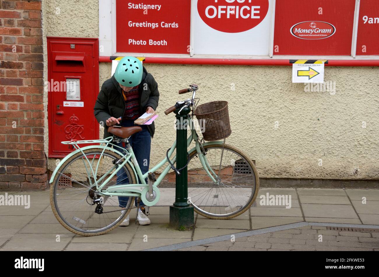 Dame Radfahrer Berechnung außerhalb der Post Stockfoto