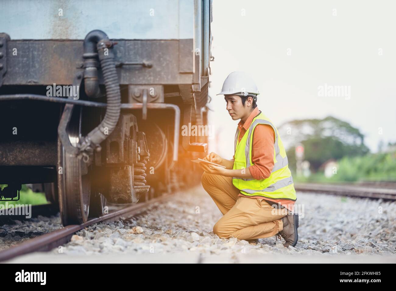 Ingenieur Mann sitzt auf der Eisenbahninspektion. Bauarbeiter auf der Eisenbahn. Techniker arbeiten mit dem Tablet, um über den Zug zu berichten. Stockfoto