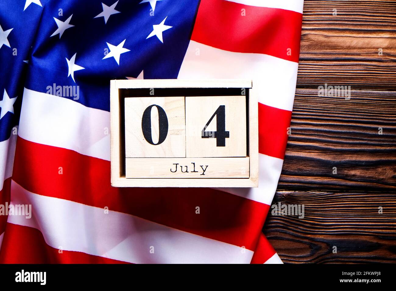 Gekräuselte amerikanische Flagge und Holzwürfelkalender mit Datum des 4. Juli, USA Independence Day auf braunem Holz Vintage-Tisch, Copy Space Hintergrund. US-Patr Stockfoto