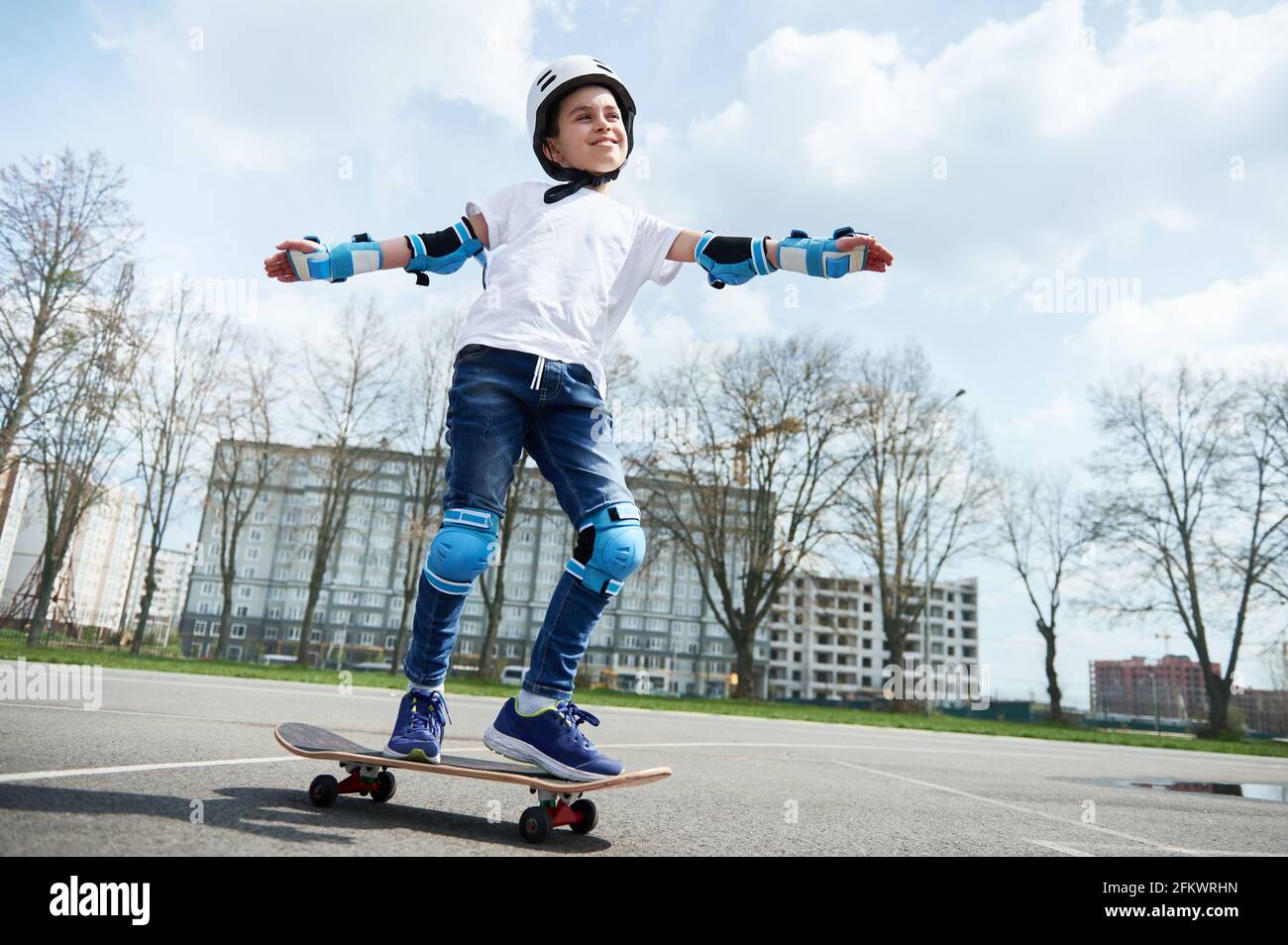 Fröhlich und lächelnd Schuljunge in Schutzkleidung und Helm hält  Balancieren Sie beim Fahren auf einem Skateboard Stockfotografie - Alamy