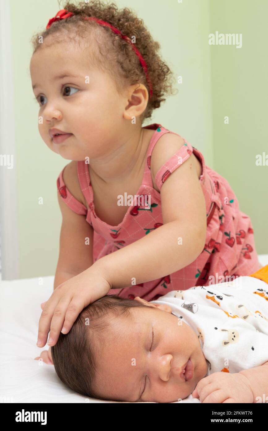 1 Jahr altes Mädchen streichelt ihren schlafenden Bruder. Stockfoto