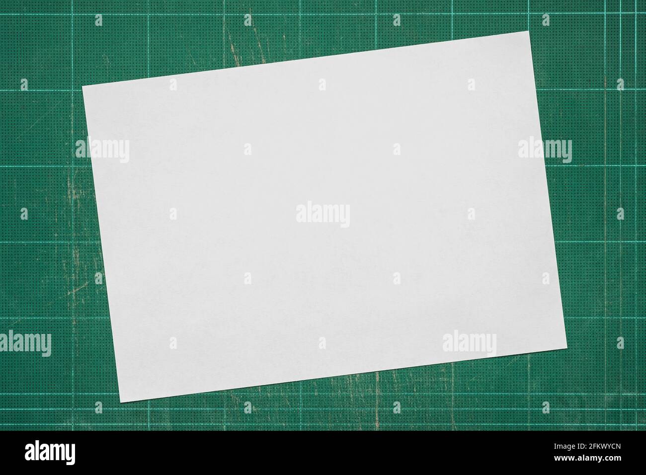 Draufsicht auf leeres weißes Papier im A4-Format auf alte grunge-grüne schmutzige Schneidematte, Platz für Text und Grafik. Stockfoto