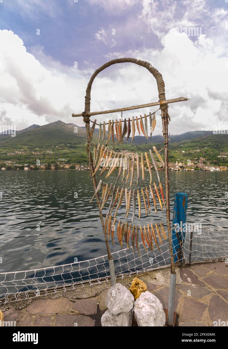 Monte Isola, Italien - 30. April 2021: Gefälschte Fische imitieren Fische, die zum Trocknen hängen, typische Nahrung von Monte Isola, der größten Seeinsel Europas. Stockfoto