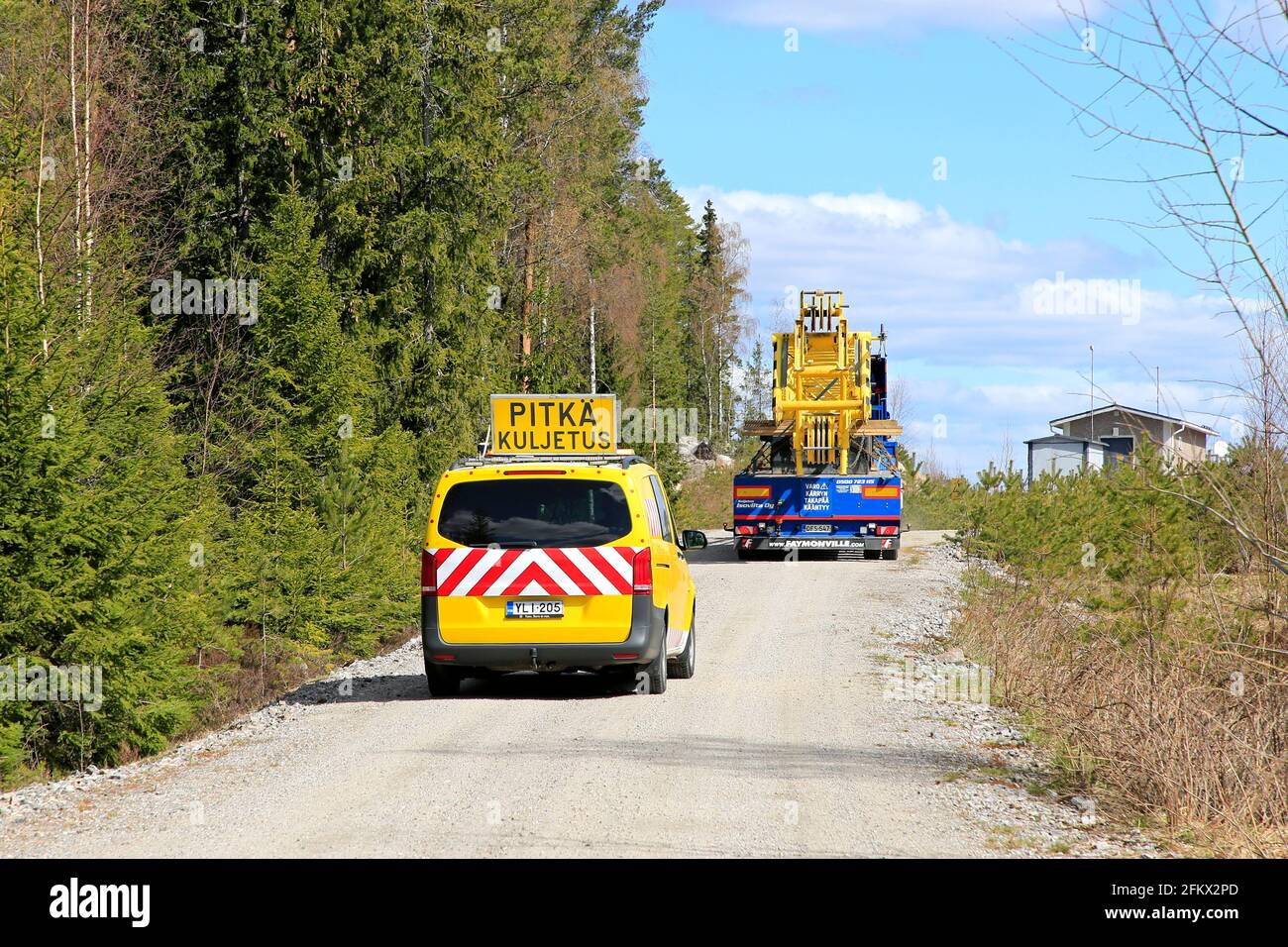 Langer Transport eines Teils des Servicekrans zum Austausch der Rotorblätter der Windenergieanlage, gefolgt von einem Begleitfahrzeug. Salo, Finnland. April 30, 2021. Stockfoto