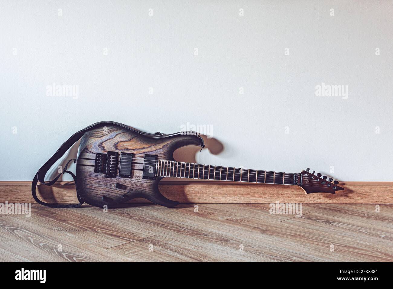 Elektrische Holzgitarre, die vor Weiß auf dem Boden liegt Wand mit Kopierbereich Stockfoto