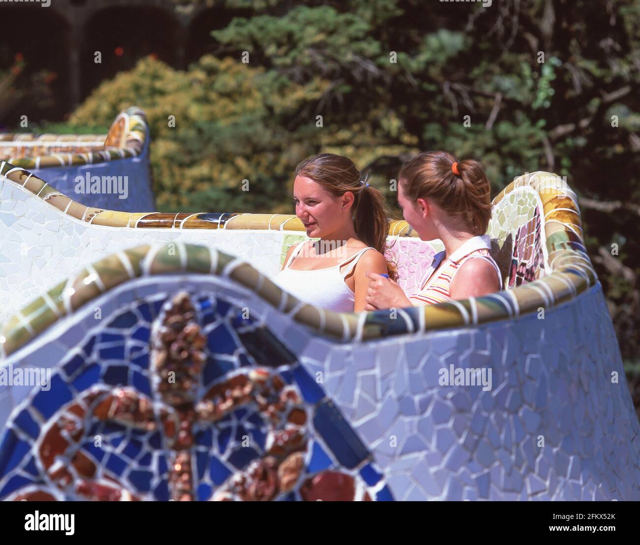 Junge Frauen sitzen auf Keramikbänken, Hauptterrasse, Park Güell, Bezirk Gràcia, Barcelona, Provinz Barcelona, Katalonien, Spanien Stockfoto