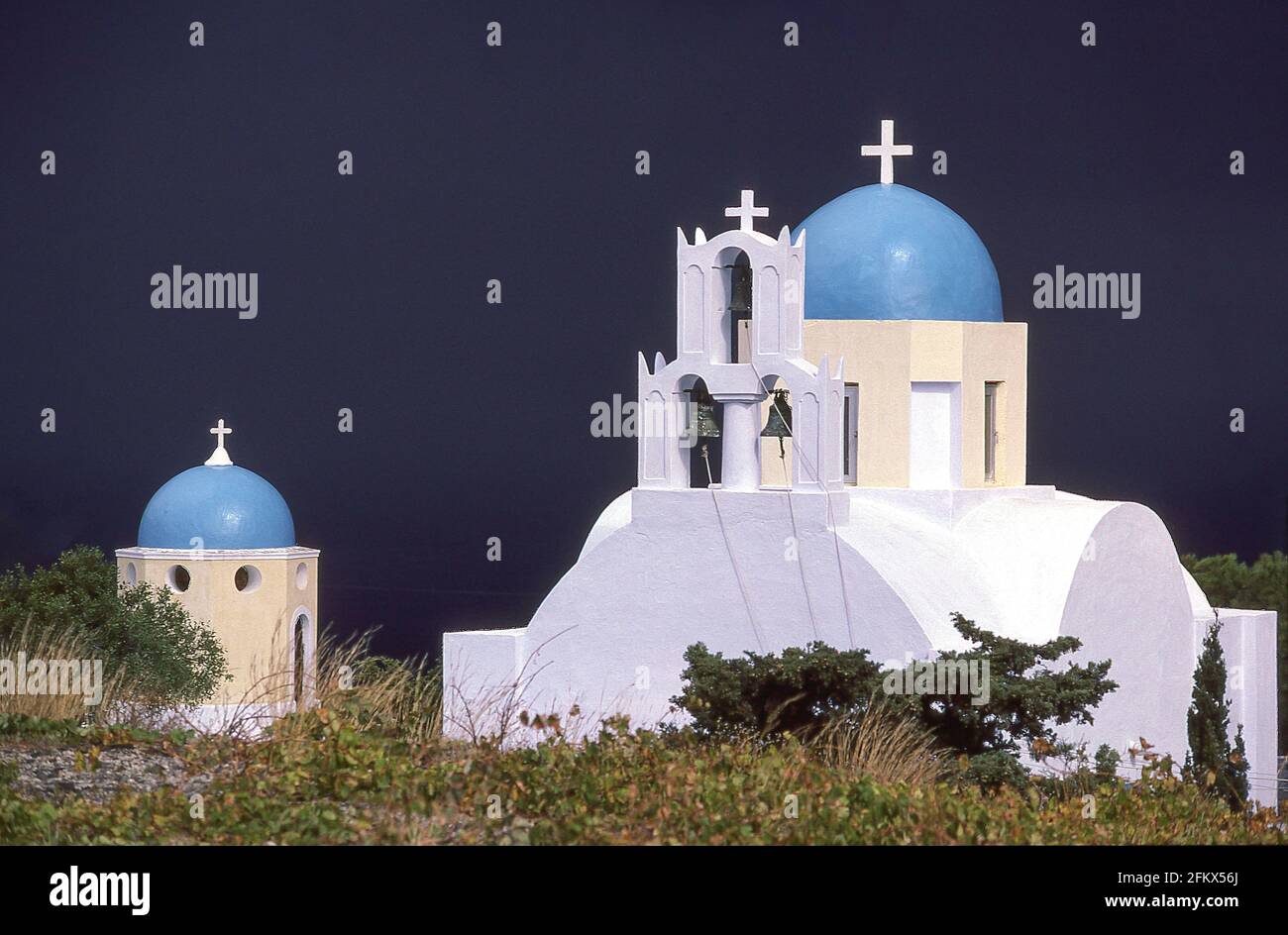 Sonnenbeleuchtete Kirche mit dunklen Sturmwolken dahinter, Fira, Santorini, die Kykladen, Südägäis, Griechenland Stockfoto
