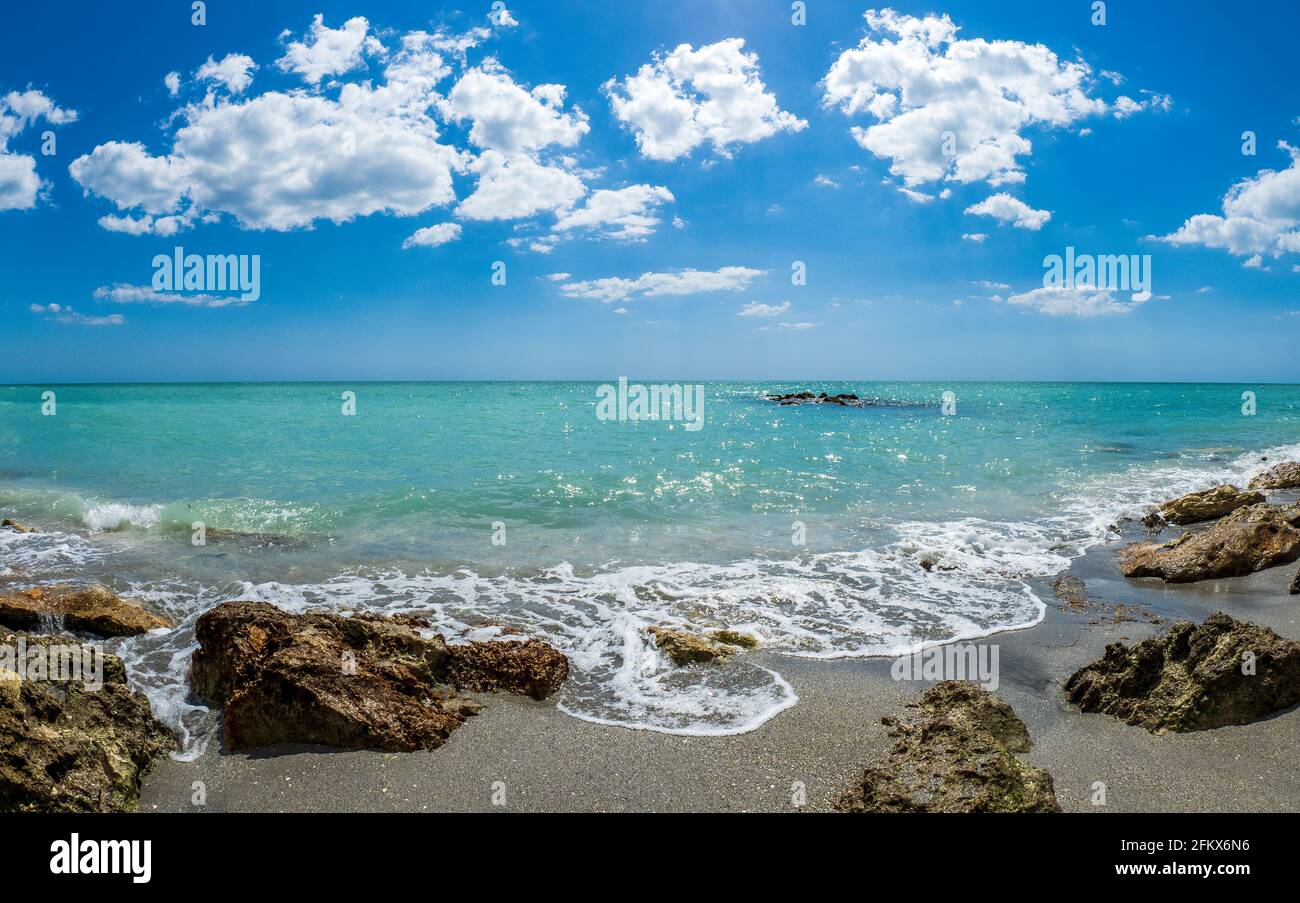 Kleine Wellen brechen unter Felsen am Ufer des Gilf von Mexiko am Caspersen Beach mit blauem Himmel und Weiße Wolken in Venedig, Florida, USA Stockfoto