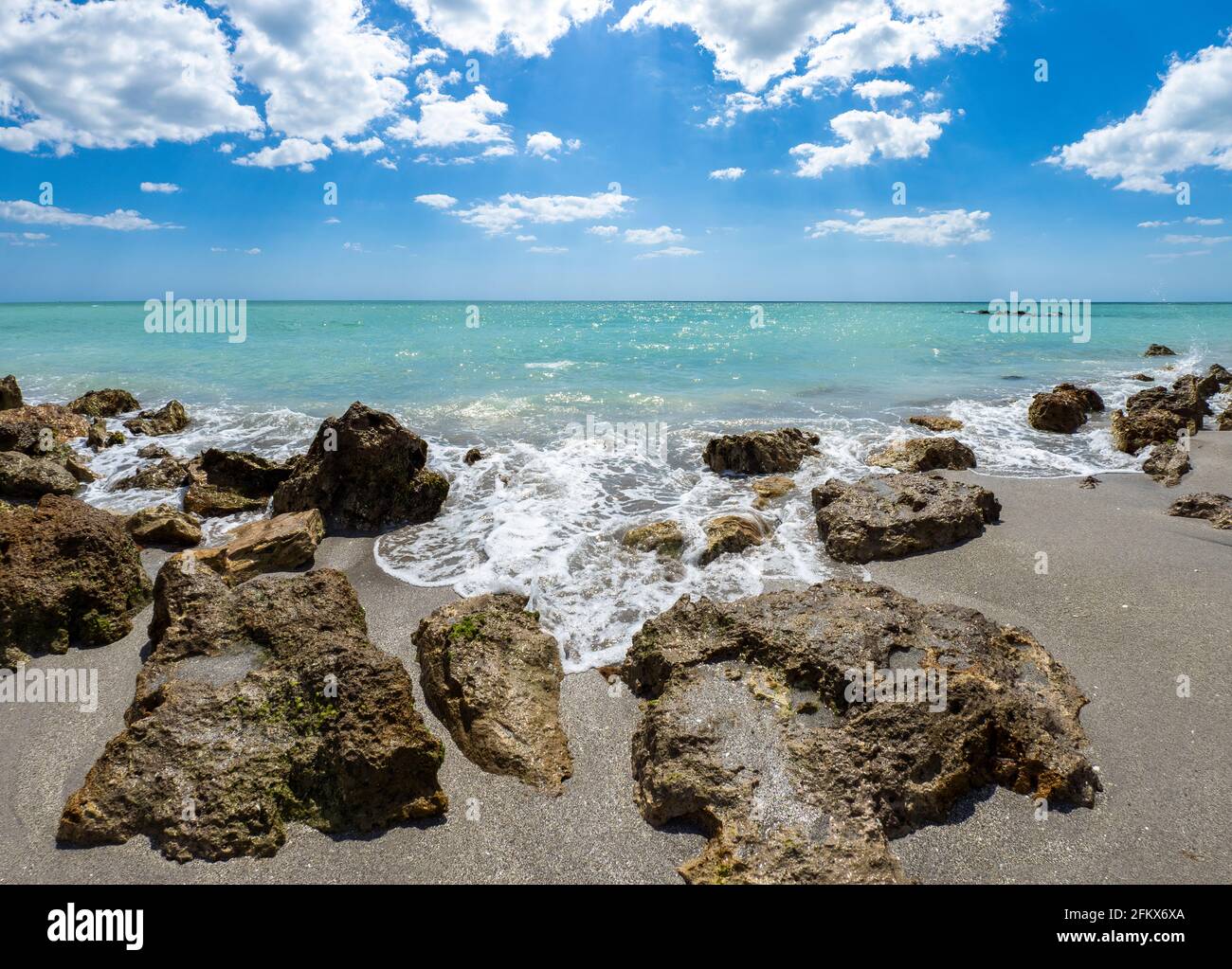 Kleine Wellen brechen unter Felsen am Ufer des Gilf von Mexiko am Caspersen Beach mit blauem Himmel und Weiße Wolken in Venedig, Florida, USA Stockfoto