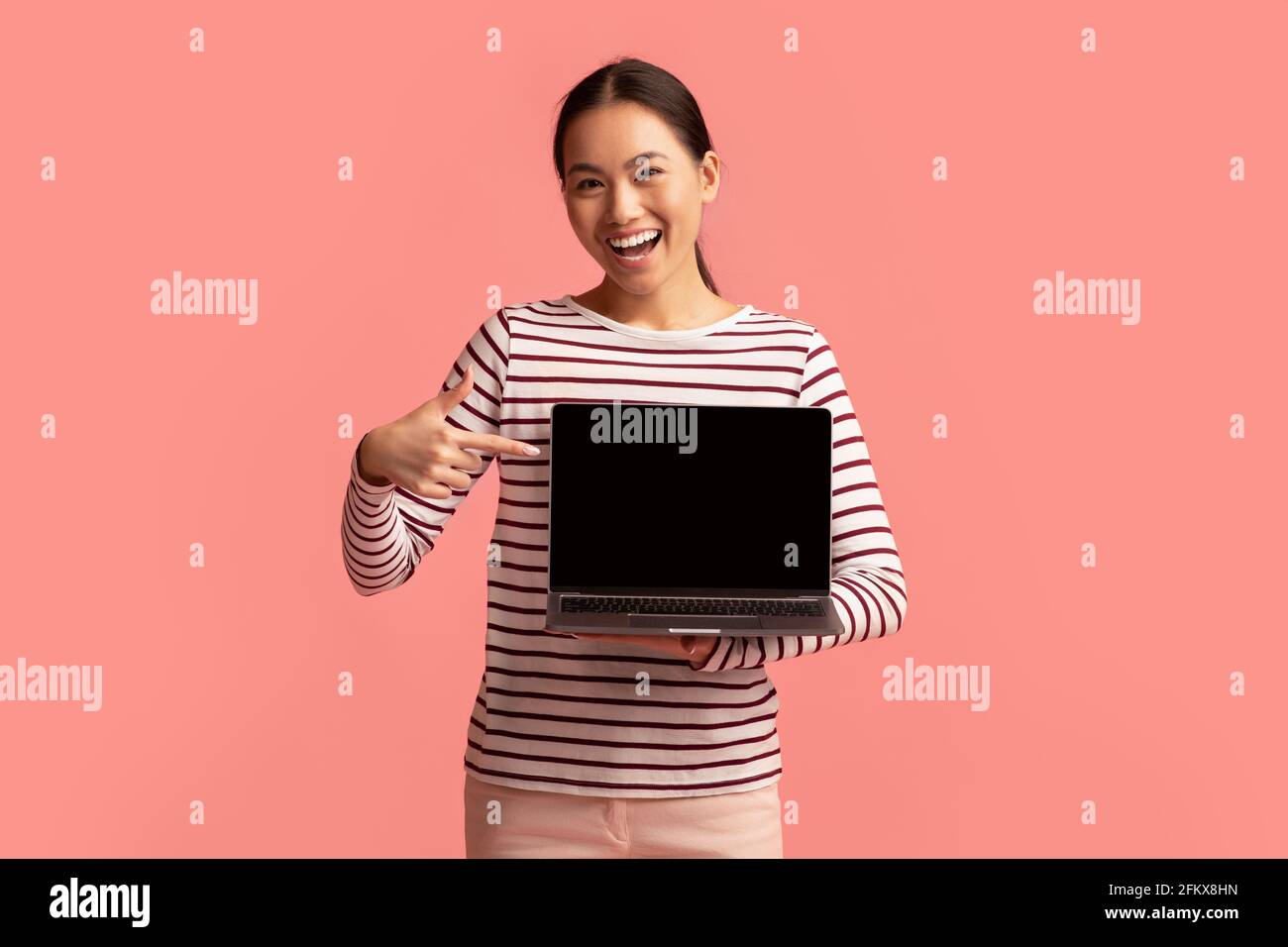Glücklich Junge Asiatische Frau Zeigt Auf Laptop Mit Schwarzem Bildschirm In Den Händen Stockfoto