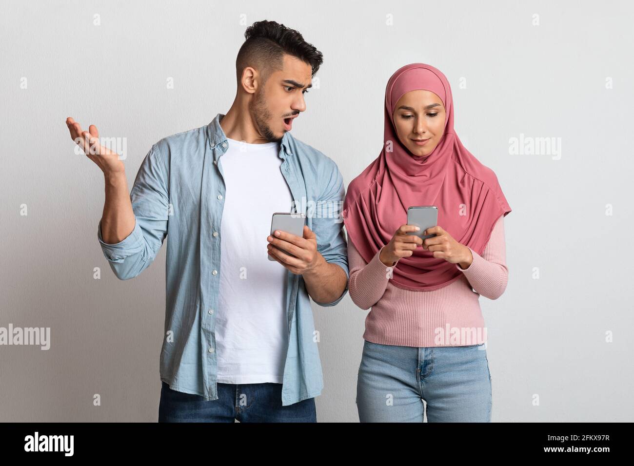 Datenschutzkonzept. Porträt eines schockierten arabischen Mannes, der das Smartphone der muslimischen Frau ansah Stockfoto