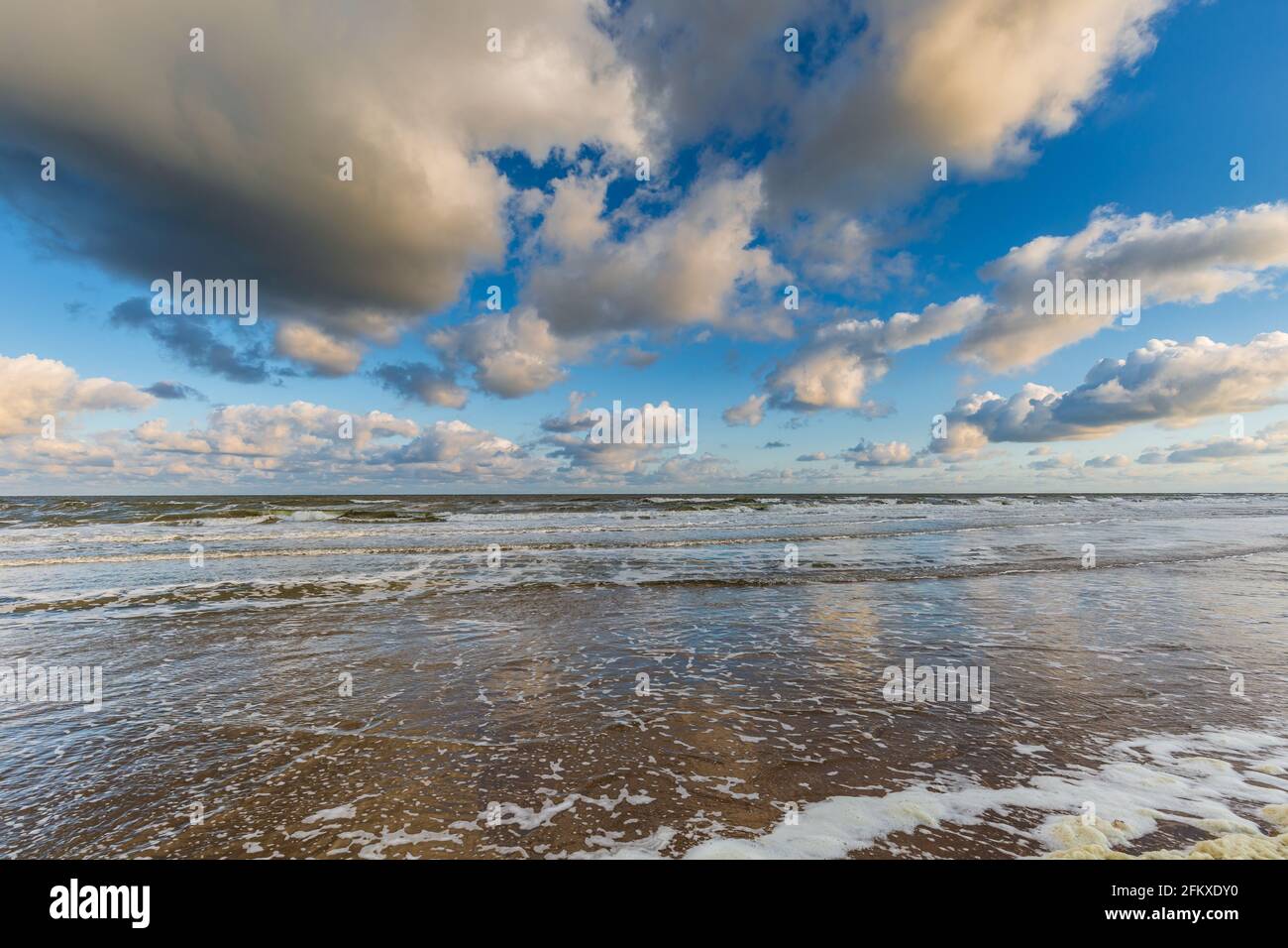 Seascape Nordseeküste bei Sonnenaufgang und Flut mit Blauer Himmel mit verstreuten Cumuluswolken und eine Brandung mit Wellen fließen am Strand mit Stockfoto