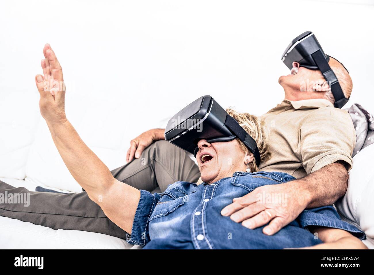 Senior reifes Paar Spaß zusammen mit Virtual reality Headset sitzt auf einem Sofa - glückliche Rentner mit modernen vr goggle Gläser - Neue tren Stockfoto