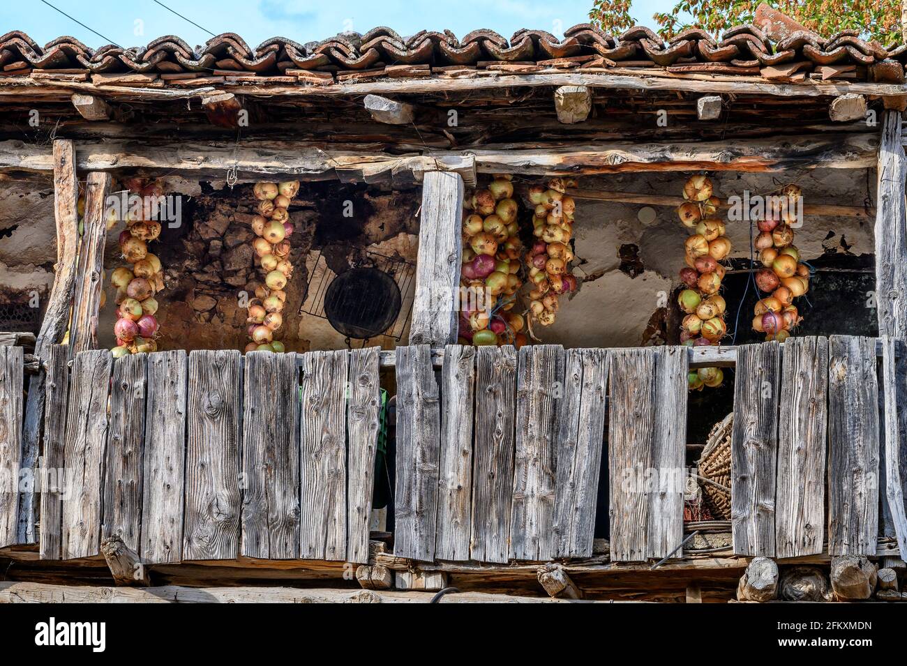 Zwiebeln hängen auf dem Balkon eines Hauses im Fischerdorf Psarades am Prespa-See, Mazedonien, Nordgriechenland. Stockfoto