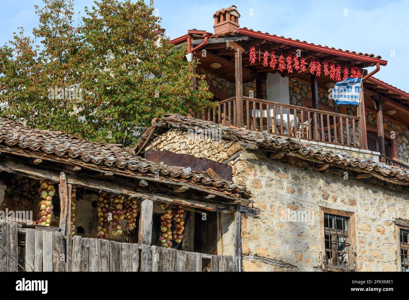 Chilischoten, Zwiebeln und eine fliegende griechische Flagge auf den Balkonen der Häuser im Fischerdorf Psarades am Prespa-See, Mazedonien, Nordgriechenlands Stockfoto