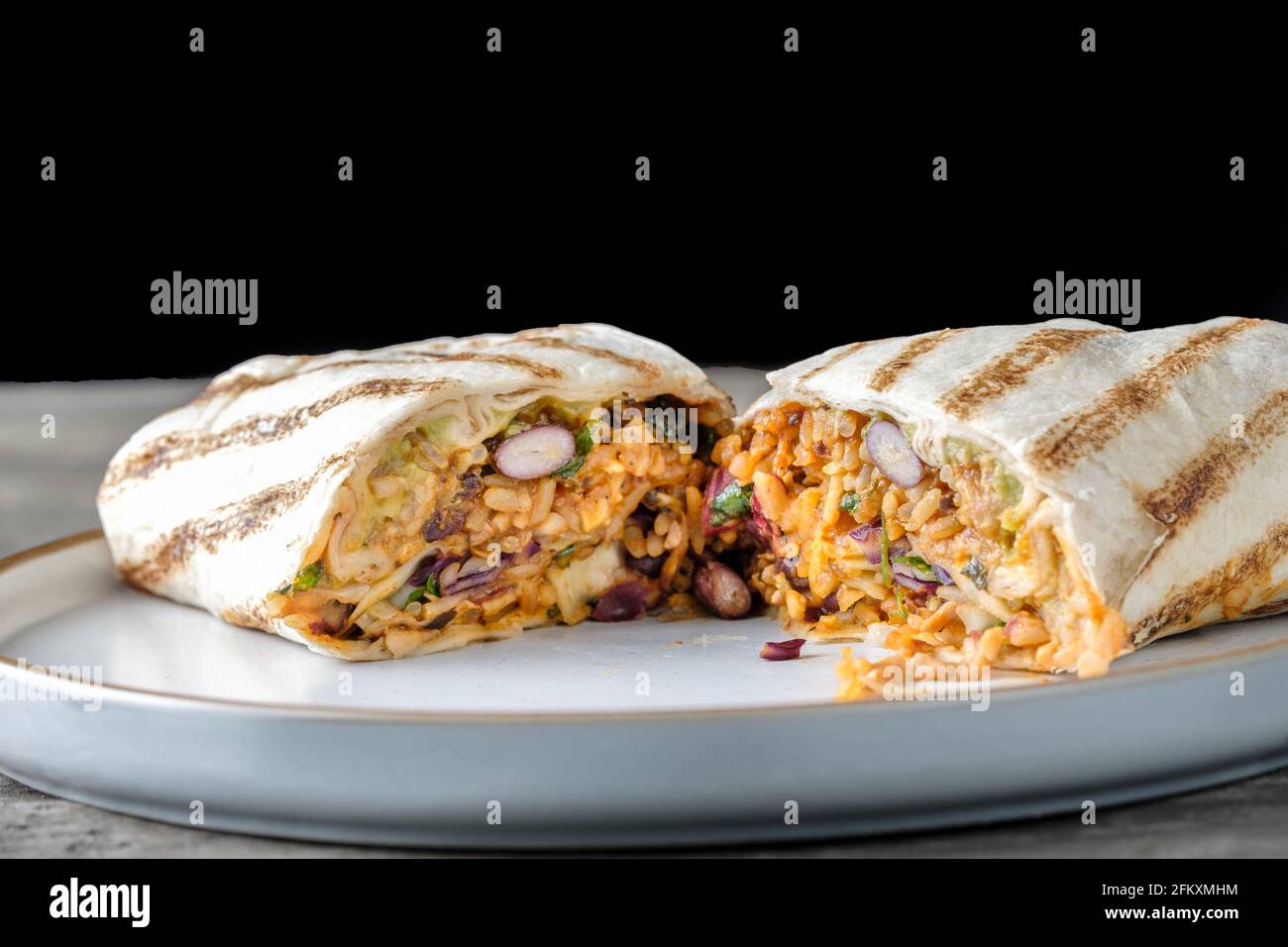 Eine vegan freundliche, frisch erwärmte Burrito-Tortilla, gefüllt mit Bohnen, Austernpilzen, gewürztem Reis und knuspriger Schlaw. Ein Fertiggericht zum Mitnehmen, mexikanisches Leckerbissen Stockfoto