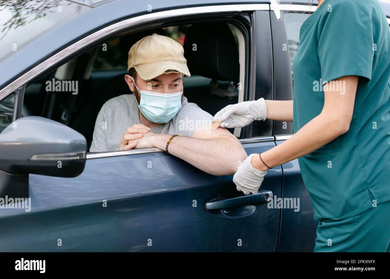 Medizinischer Assistent, der selbstklebende Bandage auf den Arm legt Stockfoto