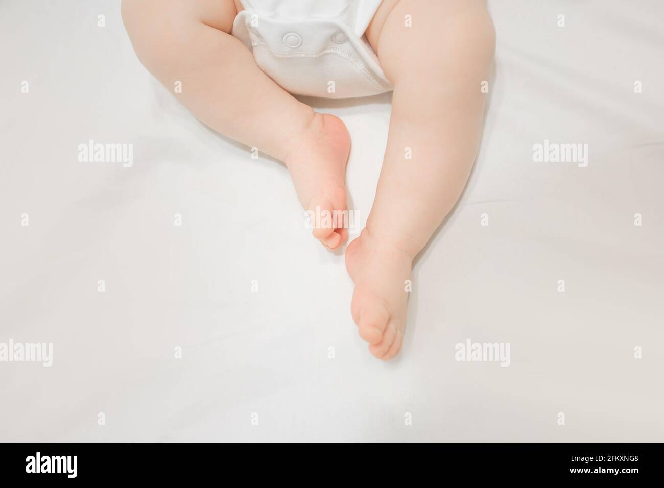 Legen in Bettlaken Baby Kleinkind Füße Zehen in weiß body Stockfoto