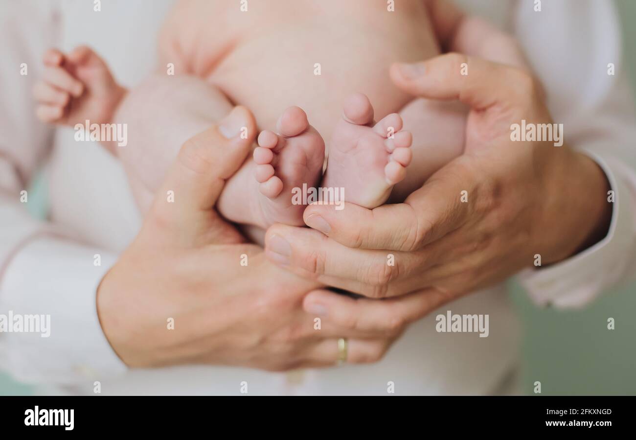 Vater Mann Hände halten kleine Füße Zehen von Neugeborenen Baby Stockfoto