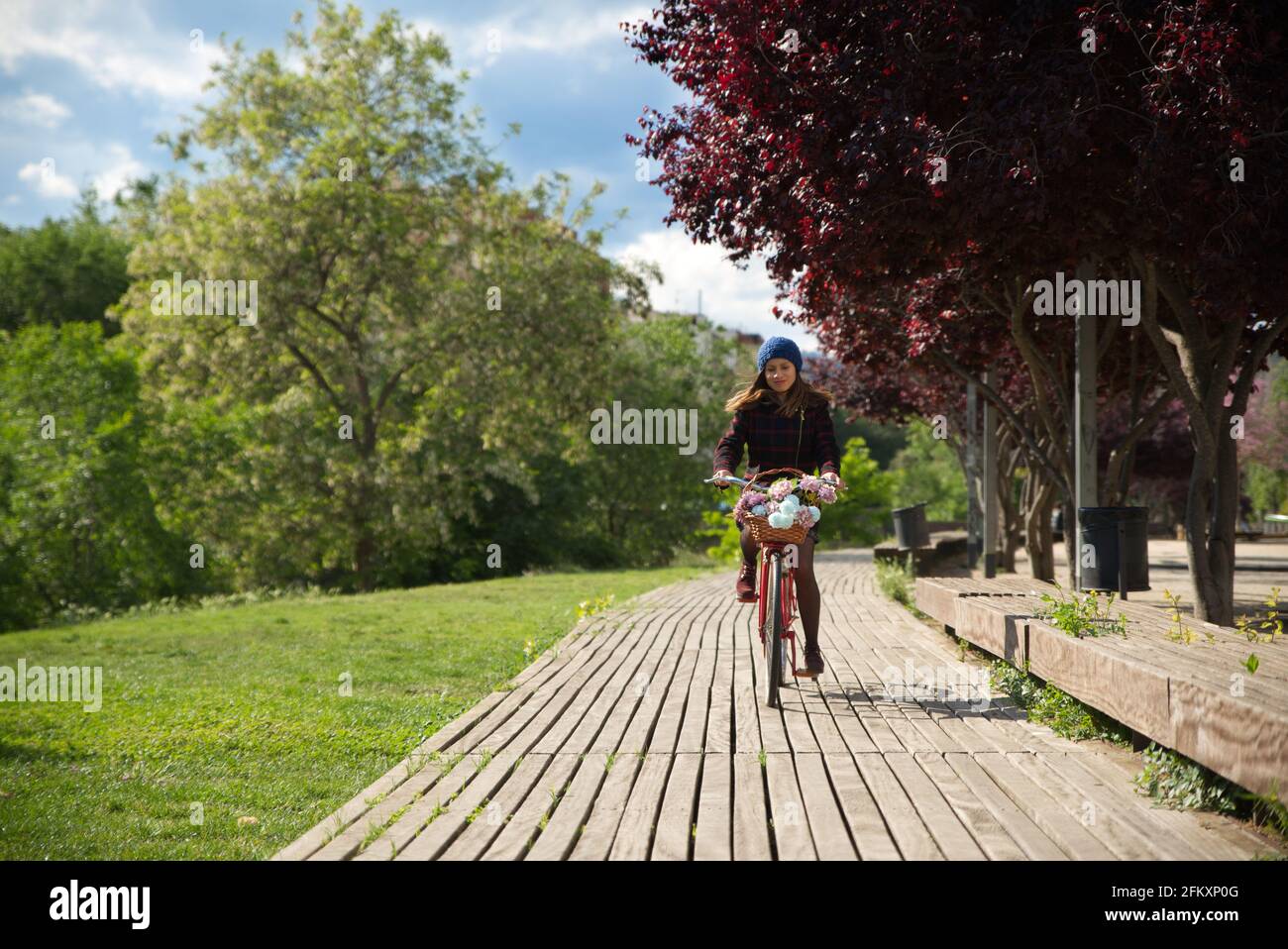 Frau auf einem roten Fahrrad mit Korb mit bunten Blumen. Stockfoto