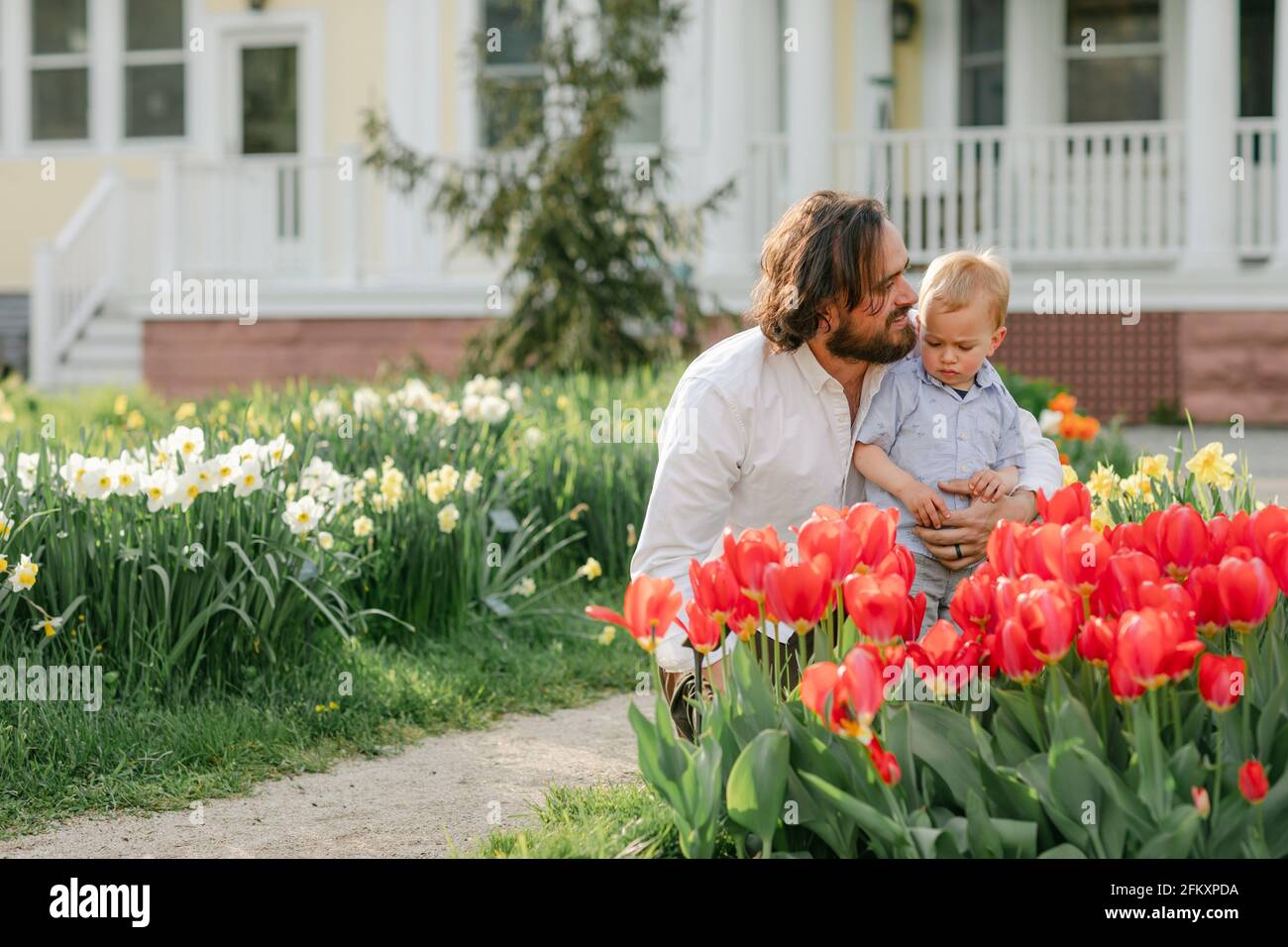 Vater unterrichtet Kleinkind Sohn über Blumen in Tulpengarten Stockfoto