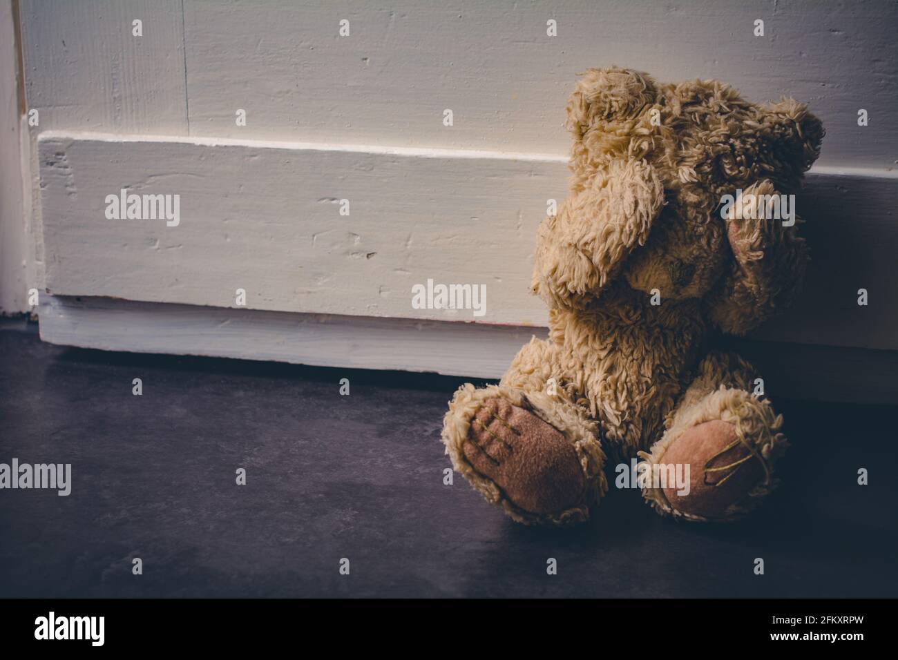Verlassene Teddy bedeckt seine Augen, sitzt an EINER Tür - Kindesmissbrauch Konzept Stockfoto