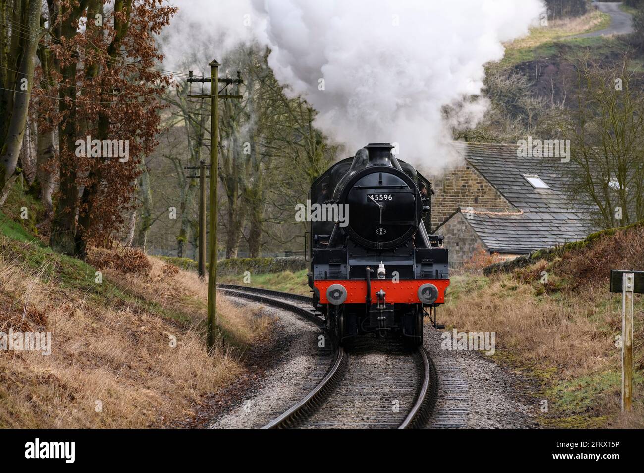 Historische Dampfeisenbahn (Lok), die auf einer Kurve in der Spur umherfährt und Rauchwolken aufbläst, die auf einer landschaftlich reizvollen Eisenbahn fahren - KWVR, Yorkshire England, Großbritannien. Stockfoto