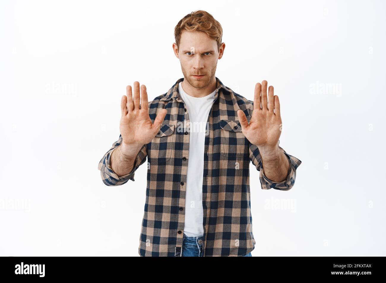 Ernster und selbstbewusster Rotschopf, der sagt, er solle aufhören, zeigt keine Verbotsgeste, tabuisiert etwas, verbietet Handlungen, schaut von unter die Stirn Stockfoto
