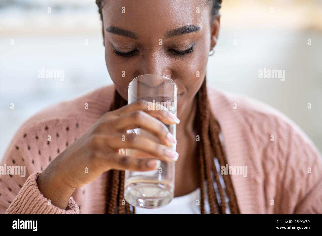 Erfrischendes Getränk. Schöne Junge Schwarze Dame Trinkwasser Aus Glas Zu Hause Stockfoto