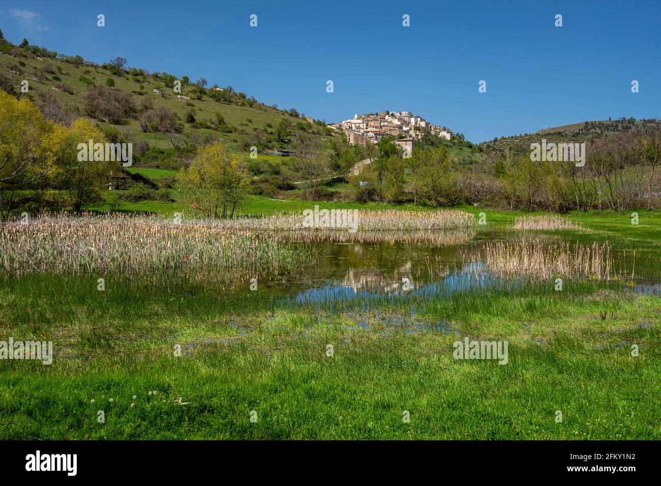 Das kleine Bergdorf San Benedetto in Perillis. Im Vordergrund ein Teich am Talgrund mit Schilf und Weiden. Abruzzen Stockfoto