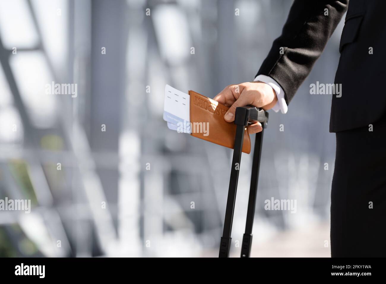 Nicht erkennbarer Geschäftsmann, der Pass und Tickets hält und Gepäck trägt Stockfoto