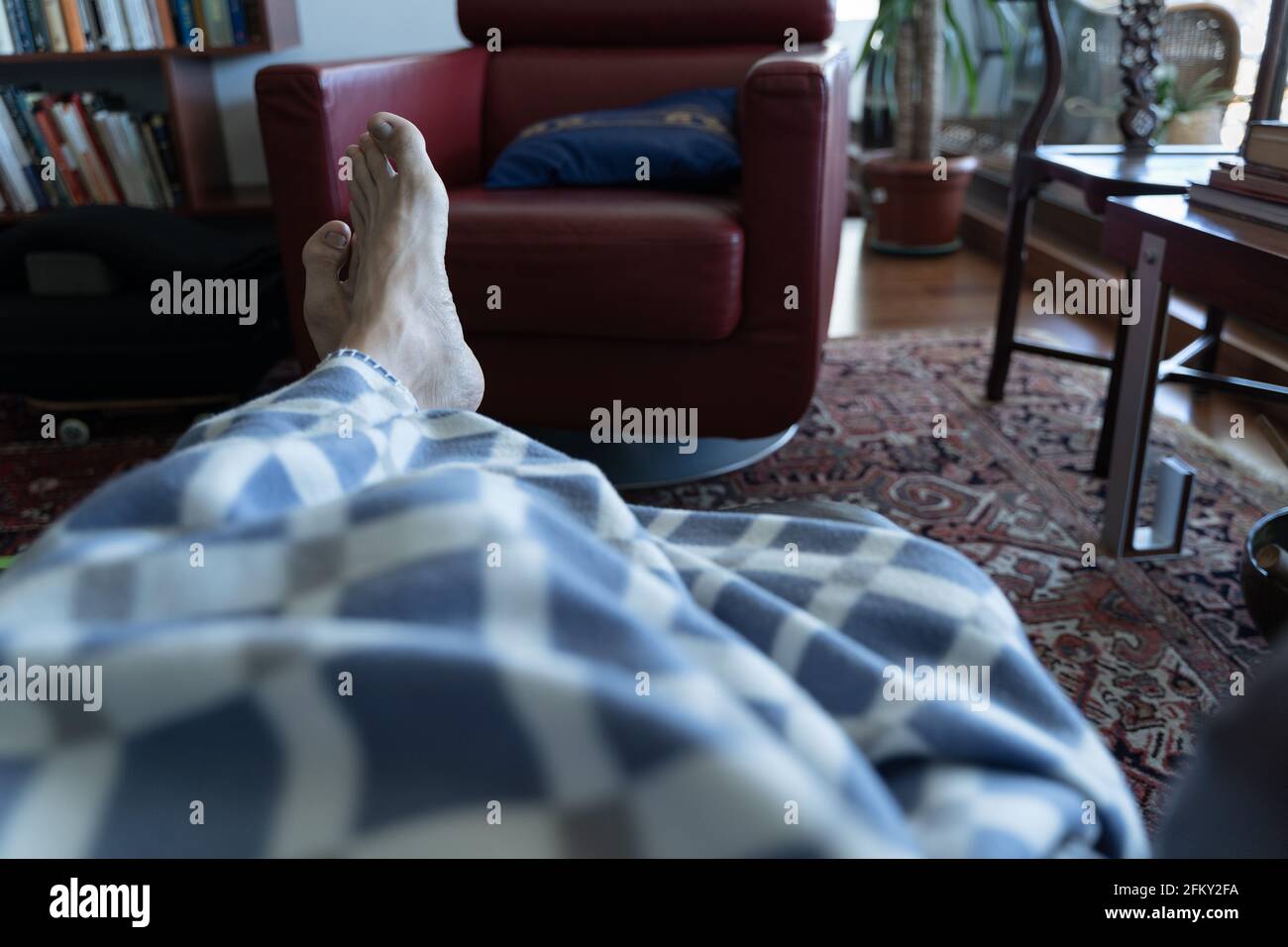 Füße eines Mannes, der über eine Decke auf der Couch rast. Mittagsschlaf, wohlfühlen zu Hause Konzepte Stockfoto