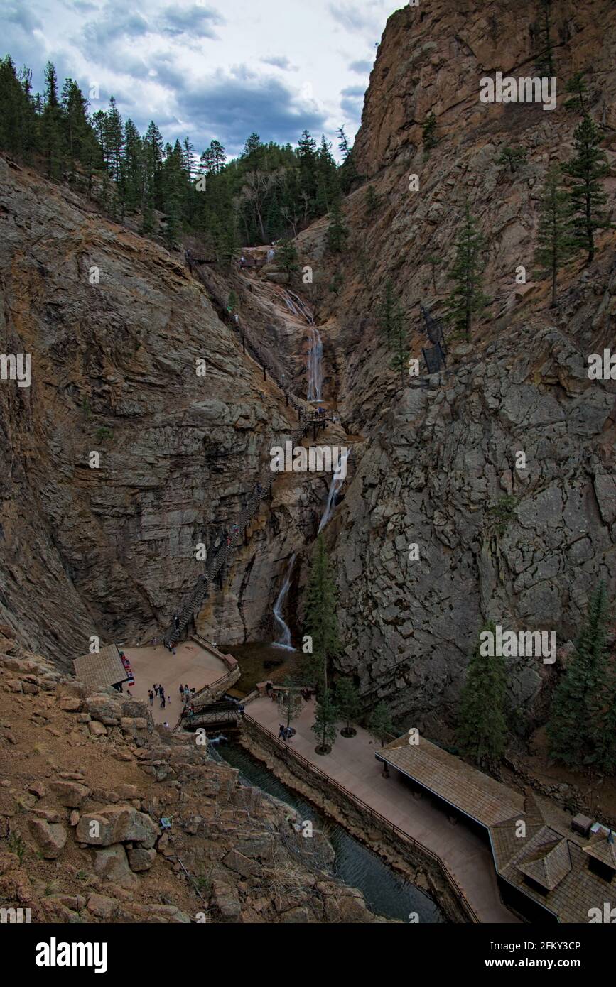 Touristen, die in Colorado Springs die sieben Stufen hinaufsteigen, um den Wasserfall zu sehen, der an den Bergklippen entlang zum Pool unter den Souvenirläden führt. Stockfoto