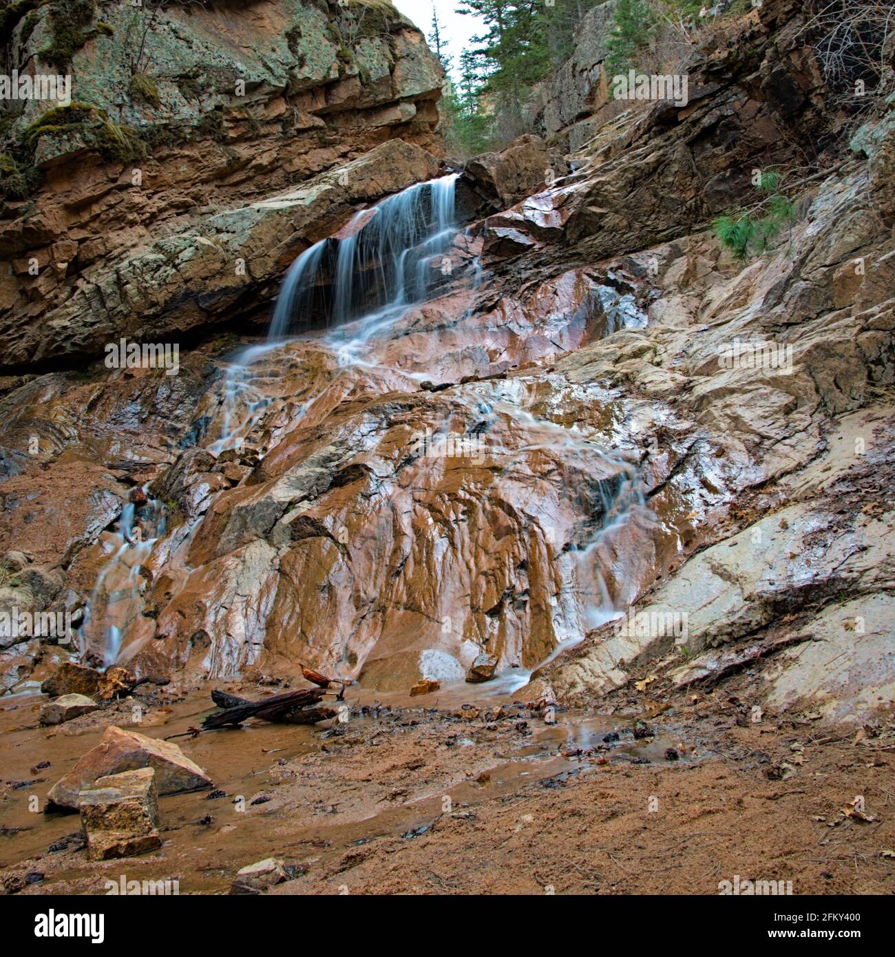 Seven Falls Colorado Springs Slow-Motion-Wasserfall, der durch Dürre und die negativen Auswirkungen des Klimawandels an der Felswand mit niedrigem Wasserstand herabstürzt. Stockfoto