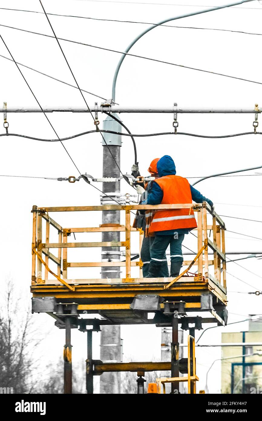 Zwei Arbeiter erhöhten die Sicherheit an einem Maschinenkran, das eine Stromleitung ausbessern soll. Stockfoto