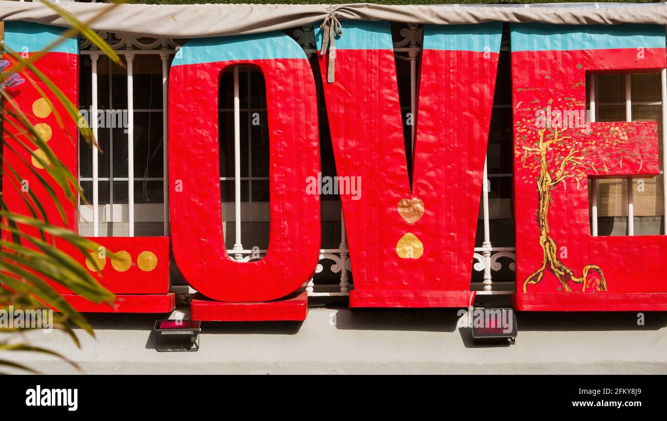 Ein riesiger Schriftzug "LOVE" als Logo zwei Meter hoch aus Holz und leuchtend rot, mit Blau und Gold verziert, mitten in der Stadt. Stockfoto