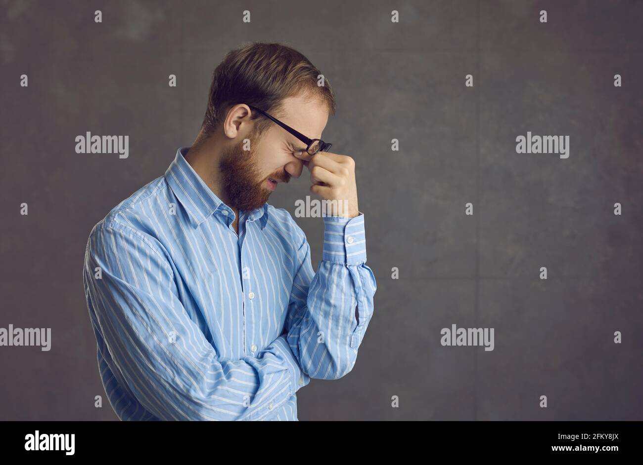 Müde junger Mann, der an Computer-Augenbelastung leidet, die ihn reibt Nach einem langen Arbeitstag Schmerzen in den Augen Stockfoto