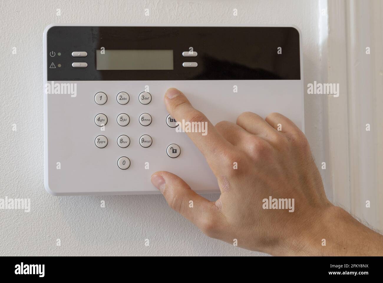 Mann, der einen Alarm in einer Wohnung aufsetzt Stockfoto