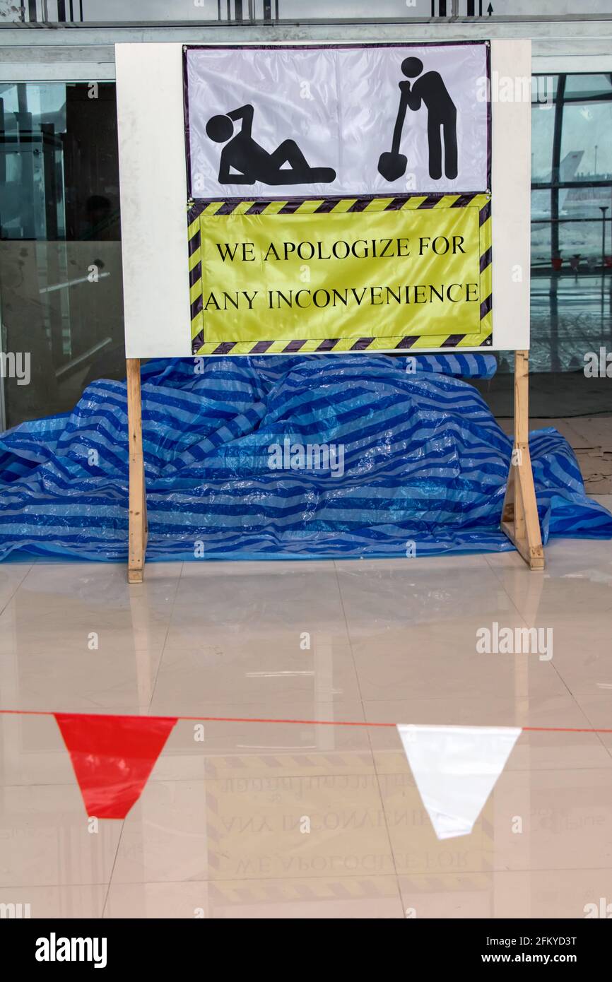 Rekonstruktion im Inneren der Halle. Eine Plakatwand mit einer Entschuldigung für die Einschränkungen der Bauarbeiten aus Gründen mit Bildern von ruhenden Arbeitern. Stockfoto