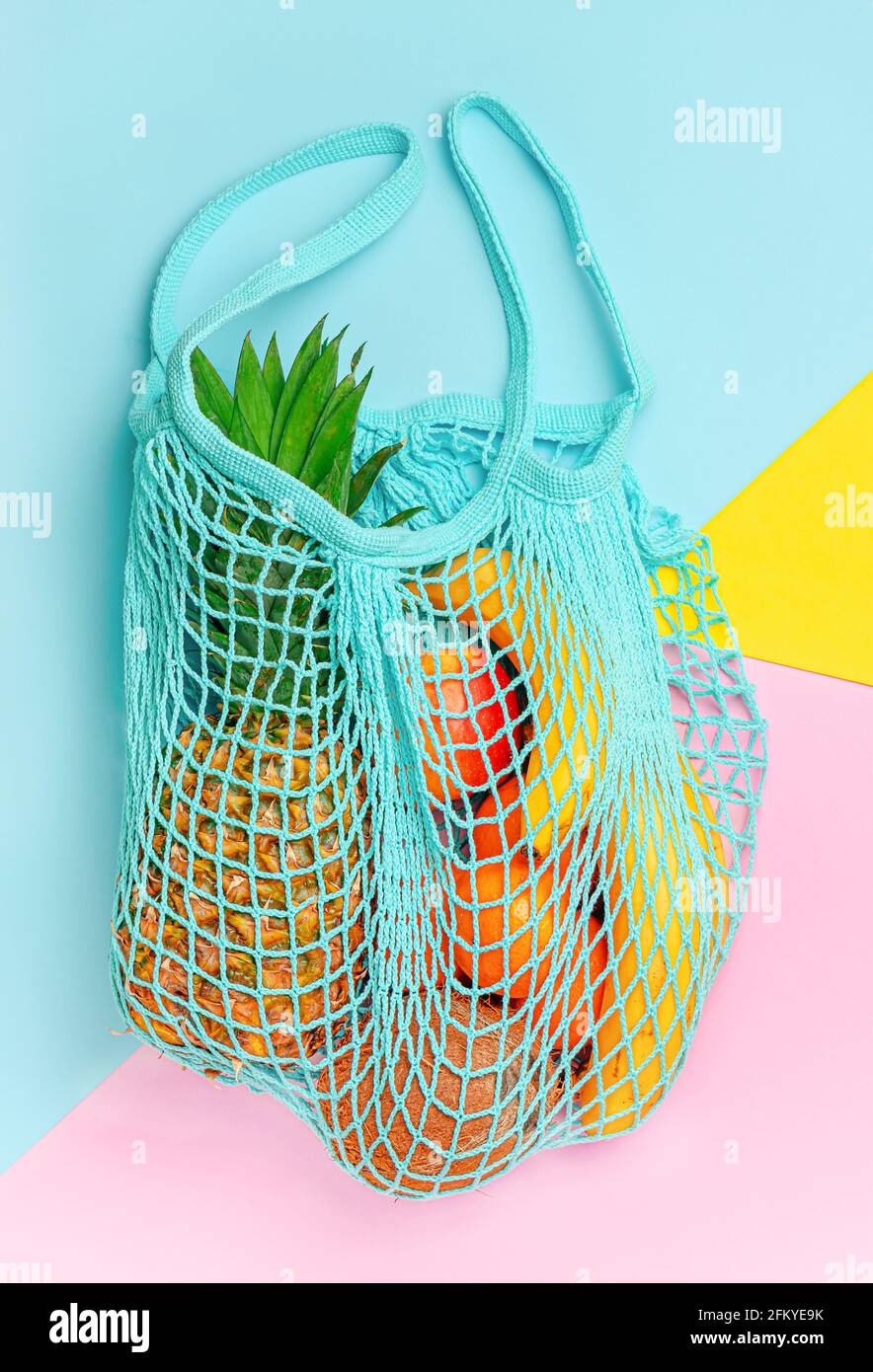 Verschiedene exotische Früchte im wiederverwendbaren Netzbeutel auf buntem Hintergrund. Ökologisches Lifestyle-Konzept. Stockfoto