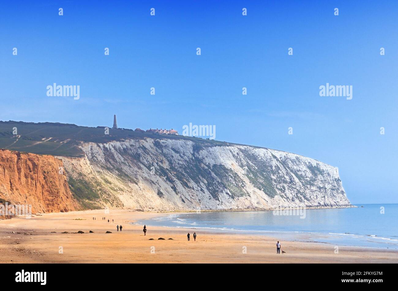 Menschen, die am Yaverland Beach unter blauem Himmel spazieren, mit Culver Down Cliff, der nördlich von Sandown Bay, Isle of Wight, England, ins Meer ragt Stockfoto