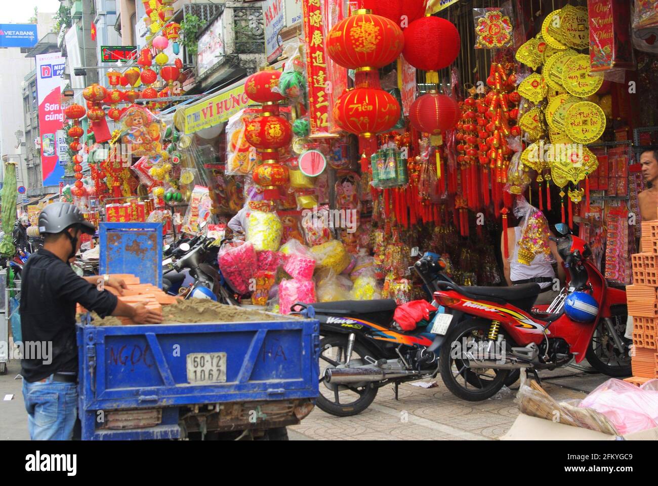 Straßenszene mit bunten, ausgefallenen Warenhäusern und Arbeitern mit Baumaterialien, Chinatown, Ho Chi Minh City, Vietnam, Asien Stockfoto