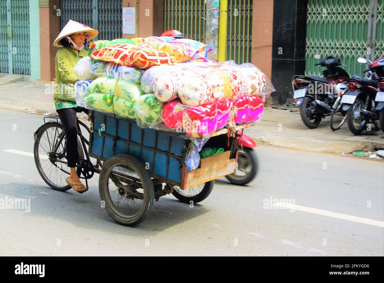 Händler mit konischem Hut transportiert große Ladung von weichen Möbeln auf Fahrrad-Rikscha, Ho-Chi-Minh-Stadt, Vietnam, Asien Stockfoto