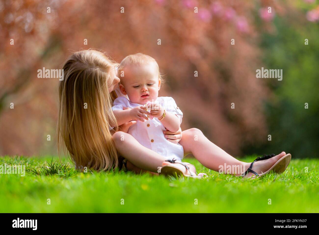 Junges Mädchen mit ihrem kleinen Bruder draußen auf der Gras Stockfoto