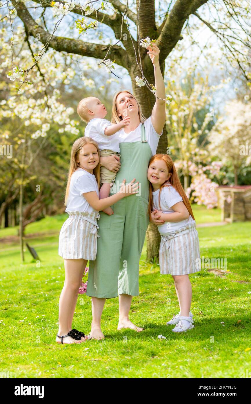 Schwangerschaftsmutter mit ihren zwei jungen Töchtern und ihrem kleinen Sohn Draußen in einem öffentlichen Park Stockfoto